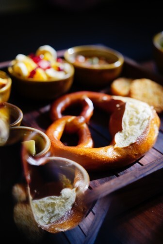 Freshly baked soft pretzel served with traditional German dips and sides on wooden platter
